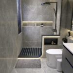 Modern grey marble bathroom with a walk-in shower, black rainfall showerhead, and white toilet.