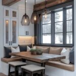 A wooden dining table with built-in banquette seating and wire pendant lights by a window.