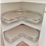 Two white corner cabinet shelves featuring rotating clear glass trays with silver metal rims.