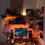 A cozy desk setup with a computer, speakers, many indoor plants, and various small decorative figurines.