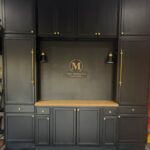 Dark charcoal built-in cabinets with a light wood countertop and a central pegboard backsplash.