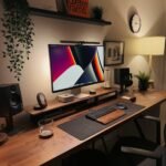 A wooden desk with a computer monitor, speakers, keyboard, and decorative plants in a home office.