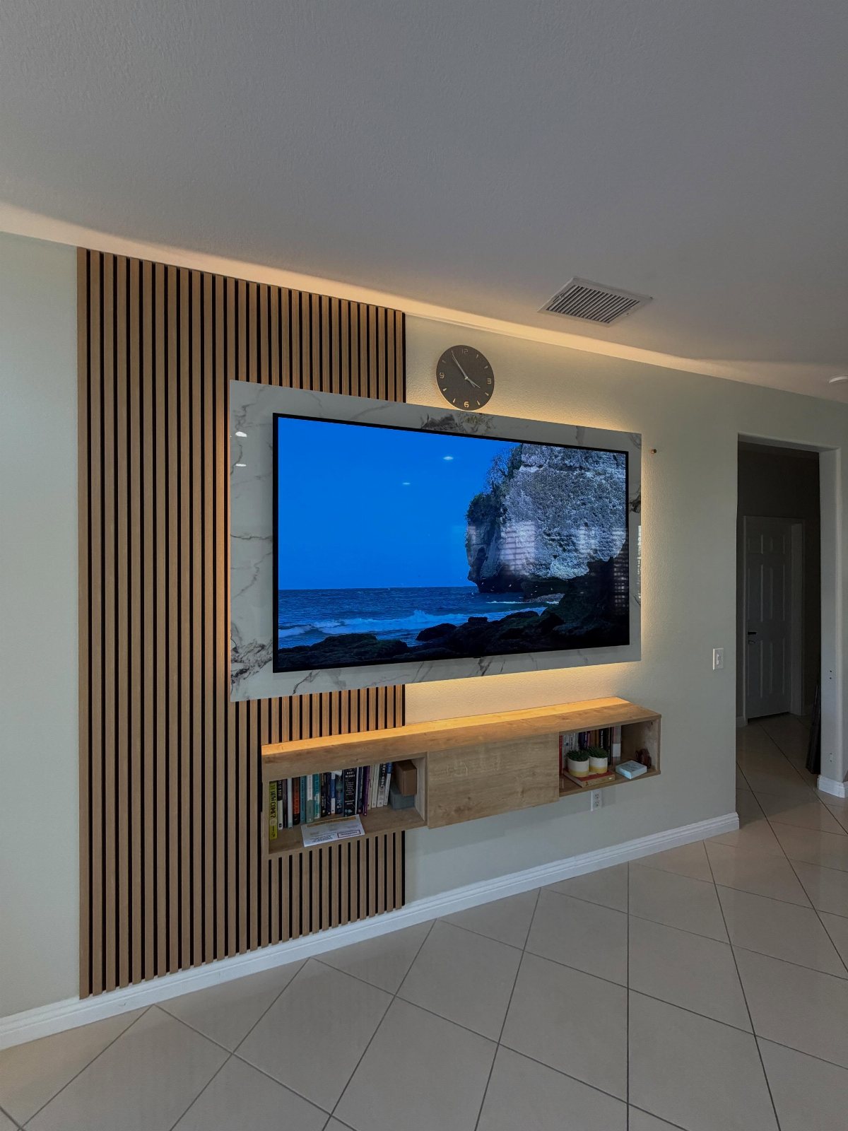 Television mounted on a marble panel against a vertical wooden slat accent wall.
